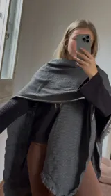 Ruana de tejido artesanal en color gris oscuro, con diseño de corte amplio y bordes desflecados.