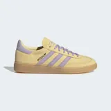 Championes Adidas modelo Handball Spezial, confeccionados en gamuza color amarillo con detalles en lila en las bandas laterales, talón y cordones. Presenta suela de caucho color caramelo y el logo Spezial en dorado en el lateral.