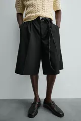 Bermuda negra de corte ancho (wide fit) con pliegues frontales, bolsillos laterales y bolsillos traseros de vivo.