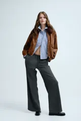 Pantalón de corte holgado y piernas rectas, confeccionado en tejido con textura de espiguilla. Presenta cintura elástica con cordón de ajuste, bolsillos laterales y bolsillos traseros decorativos.