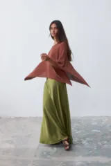 Poncho tejido color ladrillo con brillo, de corte asimétrico y cuello bote.