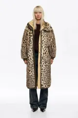 Abrigo largo reversible de corte línea A, con una cara de pelo sintético con estampado animal print y otra cara de tela técnica lisa en tono beige. Presenta capucha, cierre frontal con cremallera y botones de presión, y bolsillos laterales con cremallera.