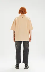 Remera de algodón premium color beige, con corte oversize, hombros caídos y cuello redondo.
