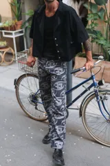 Pantalón de corte recto con estampado de logos en gris sobre fondo negro.