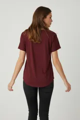 Remera de algodón color bordó, con cuello redondo a la base, mangas cortas y detalle de aplique floral bordado en el mismo tono sobre el hombro izquierdo.