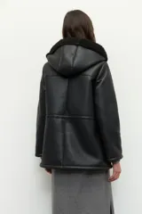 Campera tipo gamulán de cuero sintético negro con interior forrado en corderito sintético. Presenta capucha, cierre frontal con cremallera, bolsillos frontales tipo parche y cordones ajustables en la cintura.