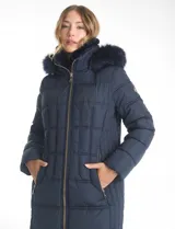 Campera puffer larga de color azul marino con capucha desmontable con borde de piel sintética. Cuenta con cierre frontal metálico dorado con logo grabado y bolsillos laterales con cierre.