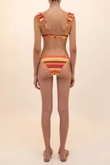 Trikini entero con estampado a rayas horizontales en tonos naranja, amarillo y rojo, con volados en la parte superior del corpiño triangular.