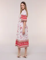 Vestido midi de estilo bohemio en color verde y blanco, con estampa floral, escote en V, cierre frontal con botones, mangas cortas amplias, cintura ajustable con lazo y volado en el bajo.