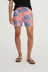Short de baño color coral con estampado de flores azules y cordón ajustable en la cintura.