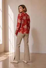 Blusa de manga larga color rojo con estampado floral en tono beige, cuello camisero y cierre frontal de botones ocultos.