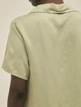 Camisa verde claro de manga corta con cuello camisero y botones.