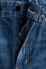 Jean de corte wide leg tiro alto, confeccionado en denim azul con efecto desgastado. Presenta diseño de cinco bolsillos, detalles trenzados a los lados y dobladillo ancho pespunteado.