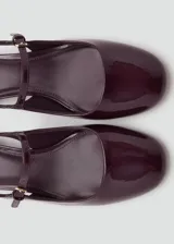 Zapato destalonado de tacón bloque bajo con acabado efecto charol, puntera redondeada y cierre de hebilla ajustable en el tobillo.