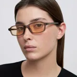 Lentes de sol con montura rectangular de color camel translúcido y cristales polarizados en tono amarillo. Diseño contemporáneo con protección UV400.