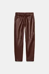 Pantalón de tiro alto confeccionado en material efecto piel, con cintura elástica ajustable mediante cordones, bolsillos delanteros y bolsillos de plastrón en la parte trasera.