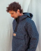 Buzo con capucha de tejido de lana texturizado en color azul jaspeado, con cierre frontal parcial y detalles en tela de lana tipo tweed en la zona del cierre.