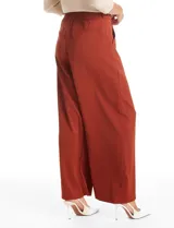 Pantalón tipo palazzo de corte ancho y fluido, confeccionado en tejido sastrero. Presenta tiro alto con doble abotonadura frontal, pinzas decorativas y cintura elástica en la parte posterior. Incluye bolsillos laterales funcionales.