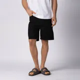Bermuda de jean de hombre, color negro, de calce regular y diseño clásico de cinco bolsillos con largo por encima de la rodilla.