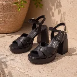Sandalias de cuero color gris plateado con plataforma, taco ancho y tira ajustable al tobillo con hebilla metálica.