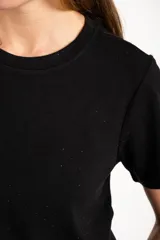 Remerón oversize de viscosa color negro con sutiles destellos brillantes, de manga corta y cuello redondo.