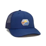Gorra tipo trucker color azul marino con malla trasera, visera curva y parche hexagonal frontal con diseño de atardecer en la playa.