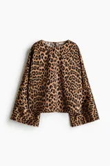 Blusa de corte holgado con estampado animal print de leopardo, escote redondo, mangas largas amplias y diseño recto.
