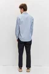 Camisa celeste de manga larga con cierre frontal de botones y cuello clásico.