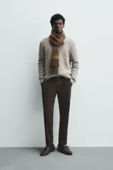 Pantalón chino de corte ajustado, color beige, con bolsillos laterales y bolsillos traseros de vivo. Cuenta con cierre frontal de cremallera y botón.