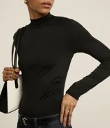 Blusa negra de mangas largas, con cuello alto y fruncidos delanteros.