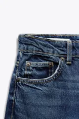 Jeans de tiro alto color negro con efecto lavado, corte mom fit, cinco bolsillos y cierre frontal con cremallera y botón metálico.