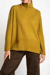 Polera de tejido de punto color mostaza, con cuello alto y calce oversize. Presenta puños y ruedo acanalados.