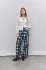 Pantalón sastrero de corte recto y tiro alto con estampado de cuadros escoceses en tonos azul marino, blanco y líneas finas en naranja. Presenta pinzas en la cintura y cierre frontal.