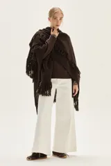 Ruana tejida de lana con diseño de sectores calados y terminación con flecos en los bordes.