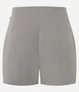Short pollera gris de corte sastrero, confeccionado en crepe de poliéster y elastano. Presenta pliegues delanteros y un detalle de cadena metálica dorada en el lateral de la cintura.