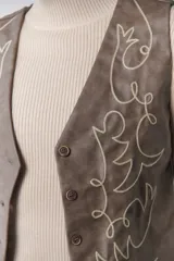 Chaleco marrón de simil cuero con bordado en color crema, cuello en V y cierre frontal con botones.