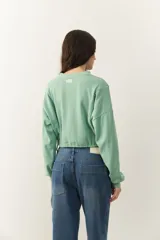 Buzo celeste cropped de manga larga con puños y cordones ajustables en la cintura.