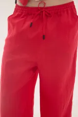 Pantalón de lino color beige, de silueta relajada, tiro medio-alto, cintura elastizada con cordón ajustable, bolsillos laterales y bolsillos traseros.