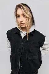 Chaleco de jean negro, de calce relajado con hombros caídos, cuello camisero, cierre frontal con botones y grandes bolsillos aplicados.