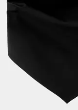 Top negro sin mangas de cuello halter drapeado, con bajo asimétrico y espalda abierta con tiras.