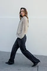 Blusa de manga larga, color marrón oscuro con estampado de lunares blancos. Presenta cuello alto con lazo ajustable en la espalda y puños elásticos.