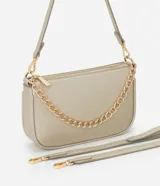 Cartera tipo shoulder baguette color dorado con textura granulada, cierre superior por cremallera, correa larga ajustable y detalle de cadena decorativa frontal en tono dorado.