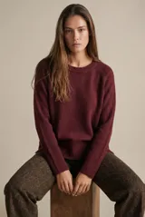 Sweater de tejido de punto color bordó, con cuello redondo, mangas largas y puños acanalados. Presenta un diseño de corte recto y textura suave.