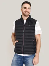 Chaleco acolchado de nailon color negro, con cuello alto, cierre frontal de cremallera con detalles distintivos de la marca y bolsillos laterales con cierre. Presenta el logo de Tommy Hilfiger bordado en el pecho.