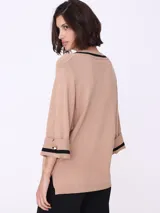 Sweater color beige de tejido de punto, con escote en V con borde negro y mangas 3/4 con puños con detalle de botón dorado.