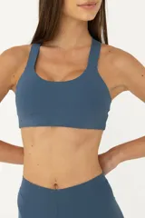 Top deportivo azul con espalda abierta y breteles finos. Tiene sujeción media y banda inferior en la cintura. Cuenta con forrería suave y liviana con abertura para colocar tazas.