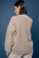 Buzo de punto en color azul marino con escote en V, puños y cuello con detalles en franjas de color turquesa y rojo. Presenta un diseño holgado de manga larga.