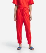 Pantalón jogger color naranja, de tiro medio, con cintura elastizada, lazo ajustable, pliegues delanteros y bolsillos laterales.