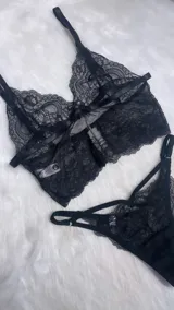 Conjunto de lencería de encaje negro compuesto por un bralette tipo crop top con tirantes ajustables y una bombacha colaless con tiras laterales decorativas.