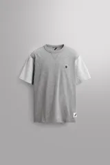 Camiseta relaxed fit de algodón, color gris melange con mangas en un tono de gris más claro. Tiene cuello redondo, manga corta, bordado frontal y texto estampado en la espalda a contraste. Incluye un parche con logo en el bajo.
